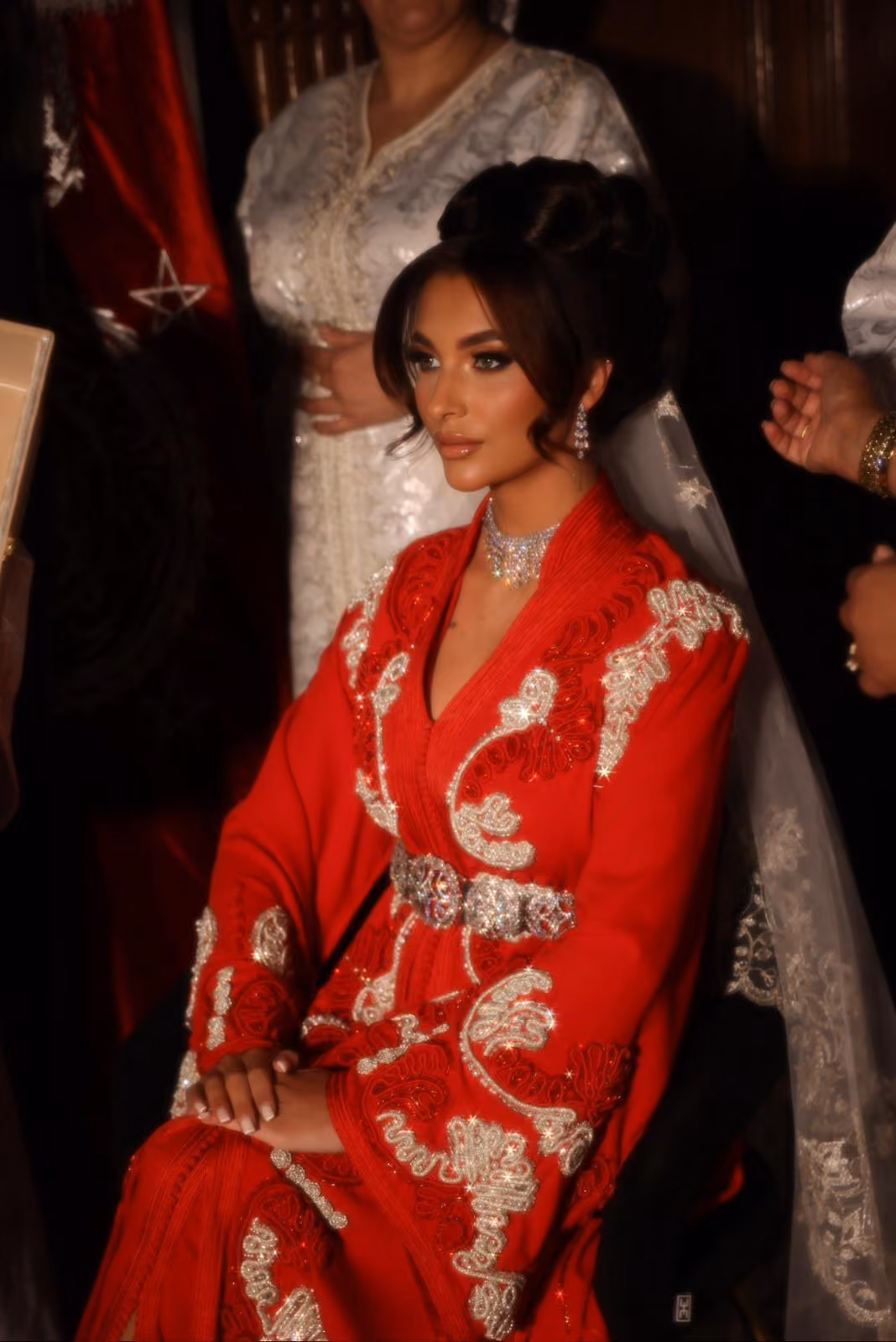 Model in een rode Marokkaanse kaftan met gouden borduursel